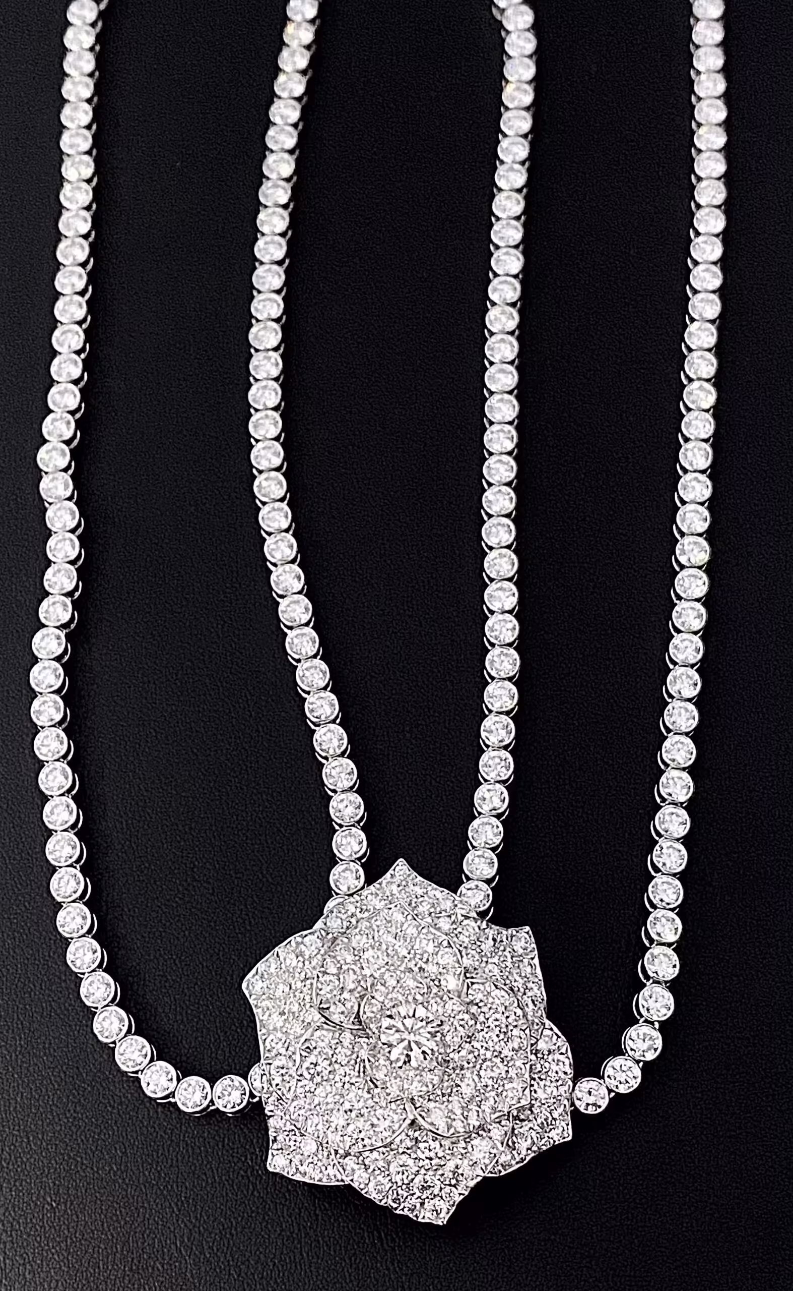 Elegante collar con colgante de rosa de diamantes y piedras brillantes sobre fondo negro.
