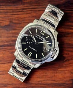 Luxury Panerai Luminor wristwatch with stainless steel band on wood.