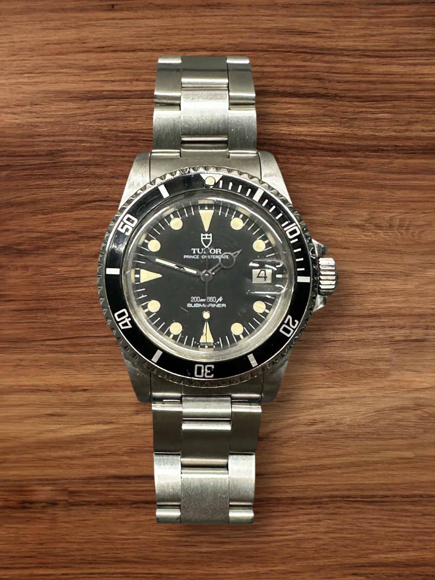 Vintage Tudor Submariner watch with black dial and stainless steel bracelet.