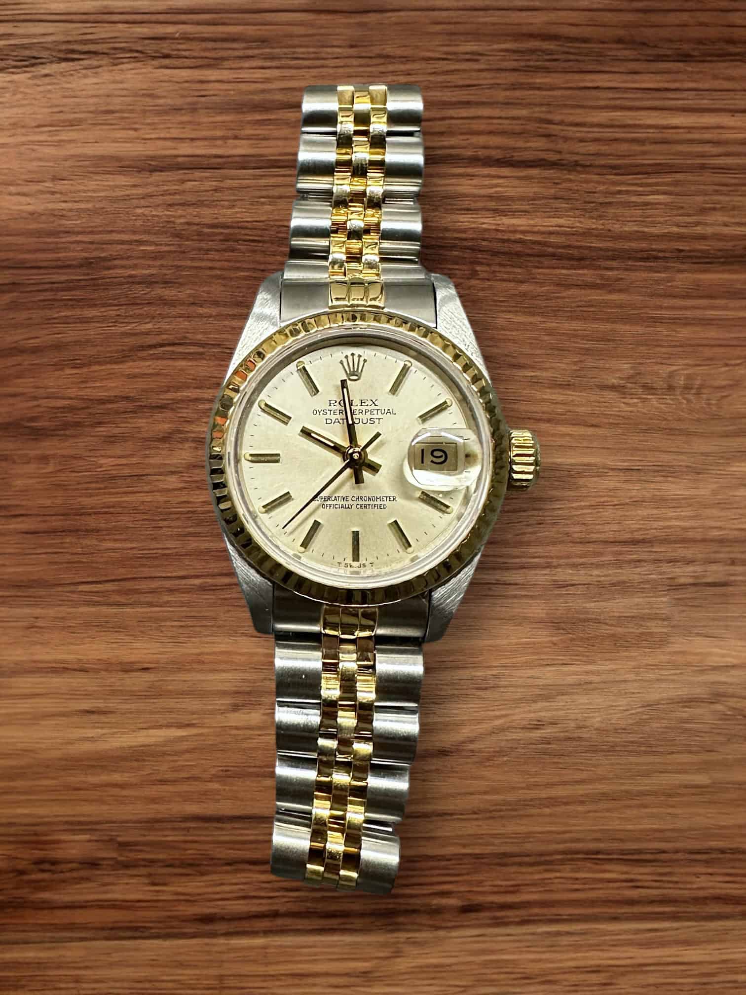 Rolex Datejust Ladies 26mm watch with gold and silver bracelet, cream dial, and date display.